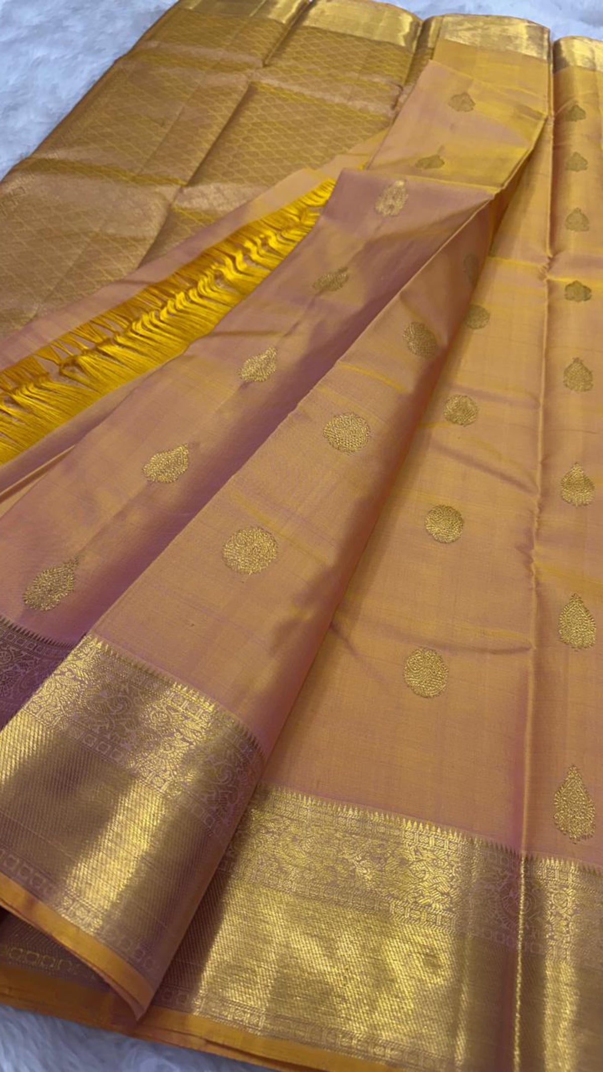 Sunset orange Kanchipuram silk saree, close-up of floral and teardrop gold zari buttas on rose-pink toned silk