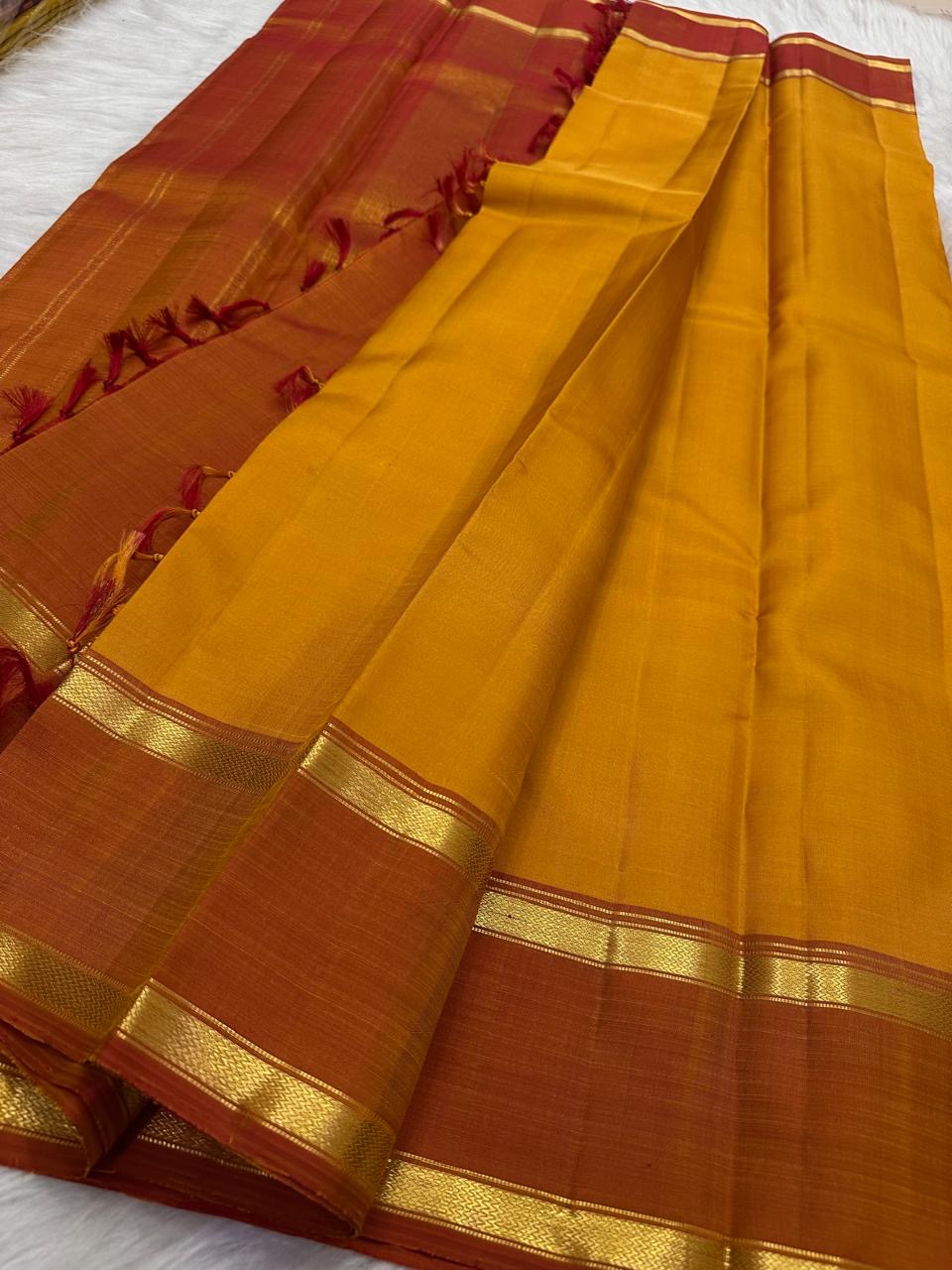 Turmeric-orange Manjal body against Arakku red border, Kanjeevaram saree close-up