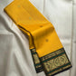 Folded yellow Kanchipuram saree showing deep green gold zari Mayil border.