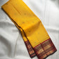 Open Turmeric Yellow Korvai saree showing scattered gold buttas and intricately layered deep Maroon zari border.