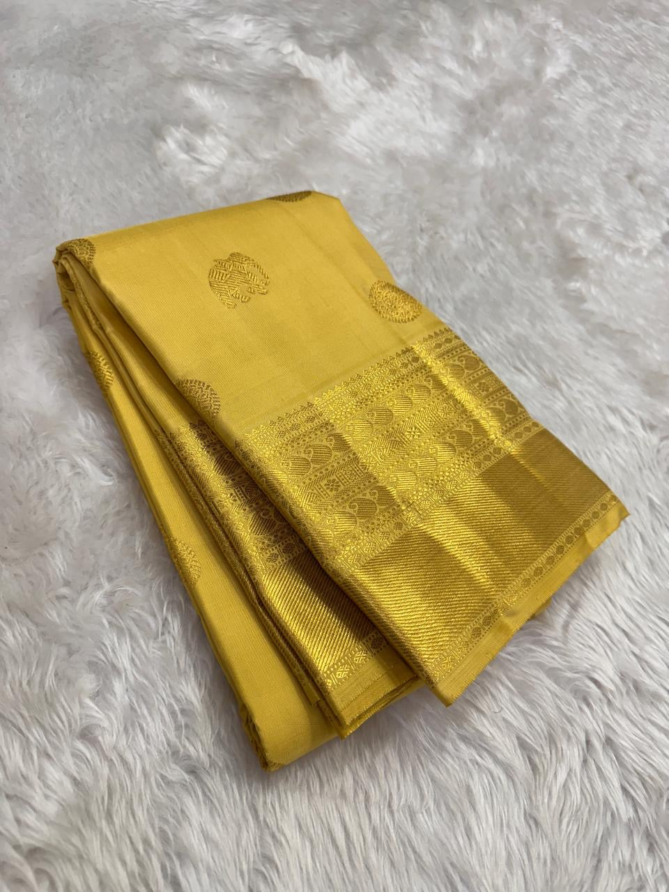 Close view of turmeric yellow Kanchipuram silk with elaborate multi-layer Kamalam zari buttas.