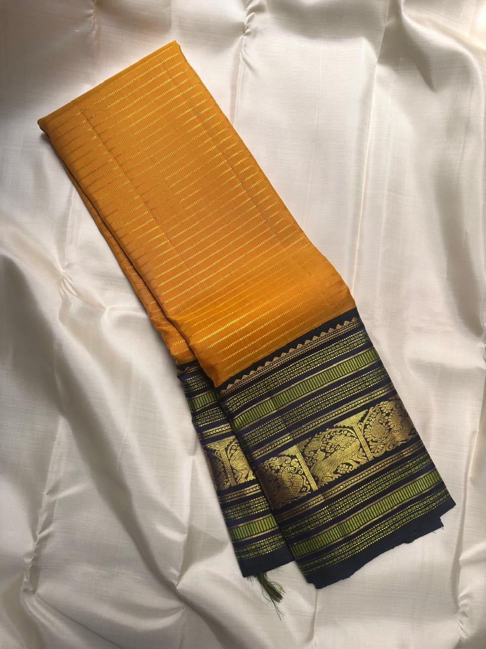 Turmeric yellow Kanjeevaram silk saree with deep navy Varisaipet border, full view