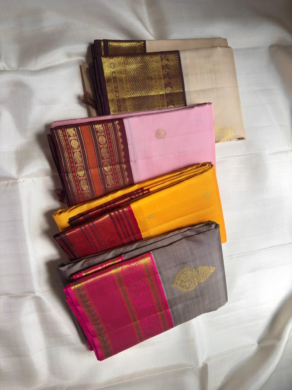 Folded Turmeric Yellow handwoven Kanchipuram Korvai saree showing ornate gold zari border against deep Maroon.