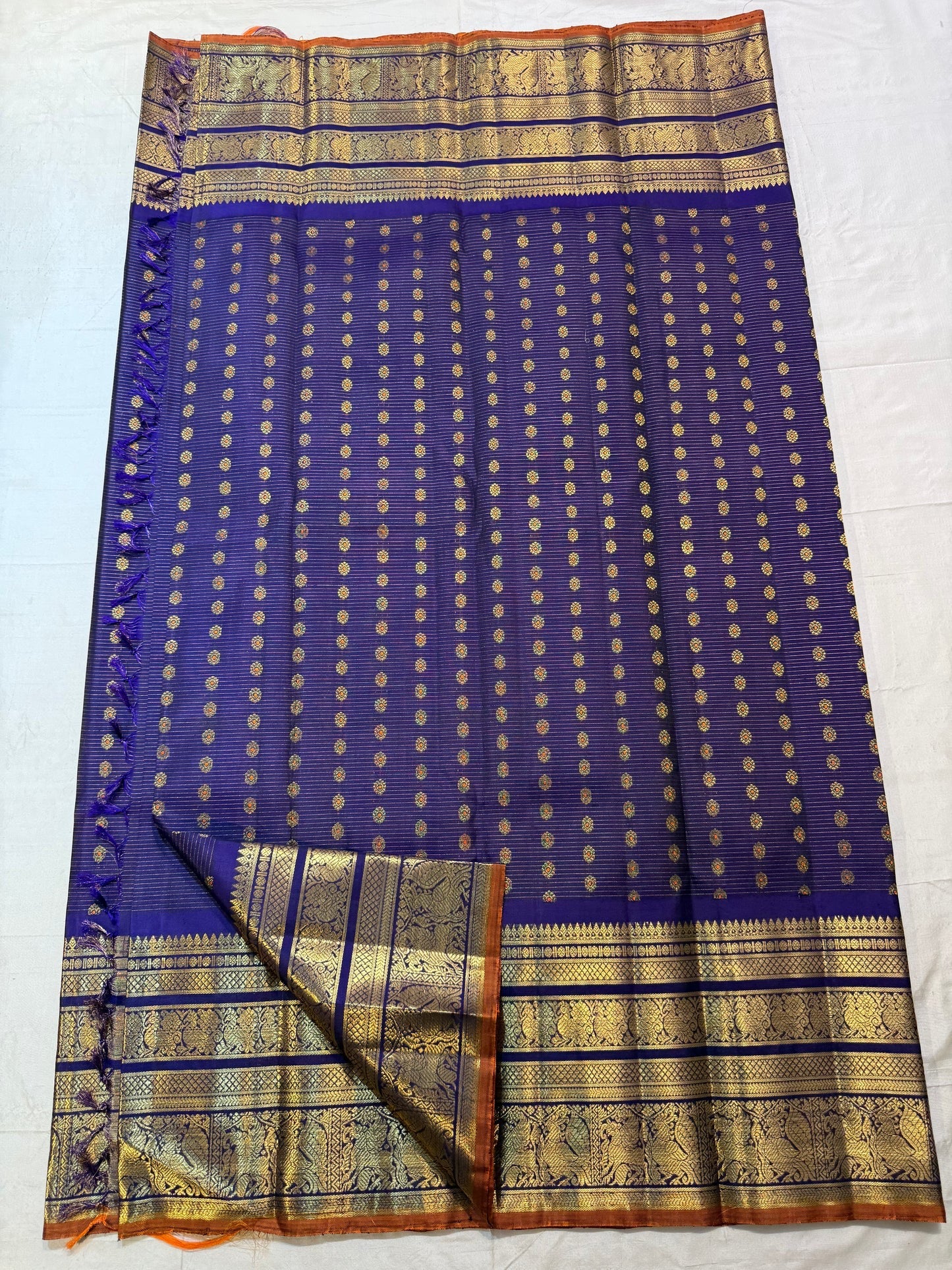 Close body view of evenly spaced gold zari buttas over fine Vairaoosi linear weaving