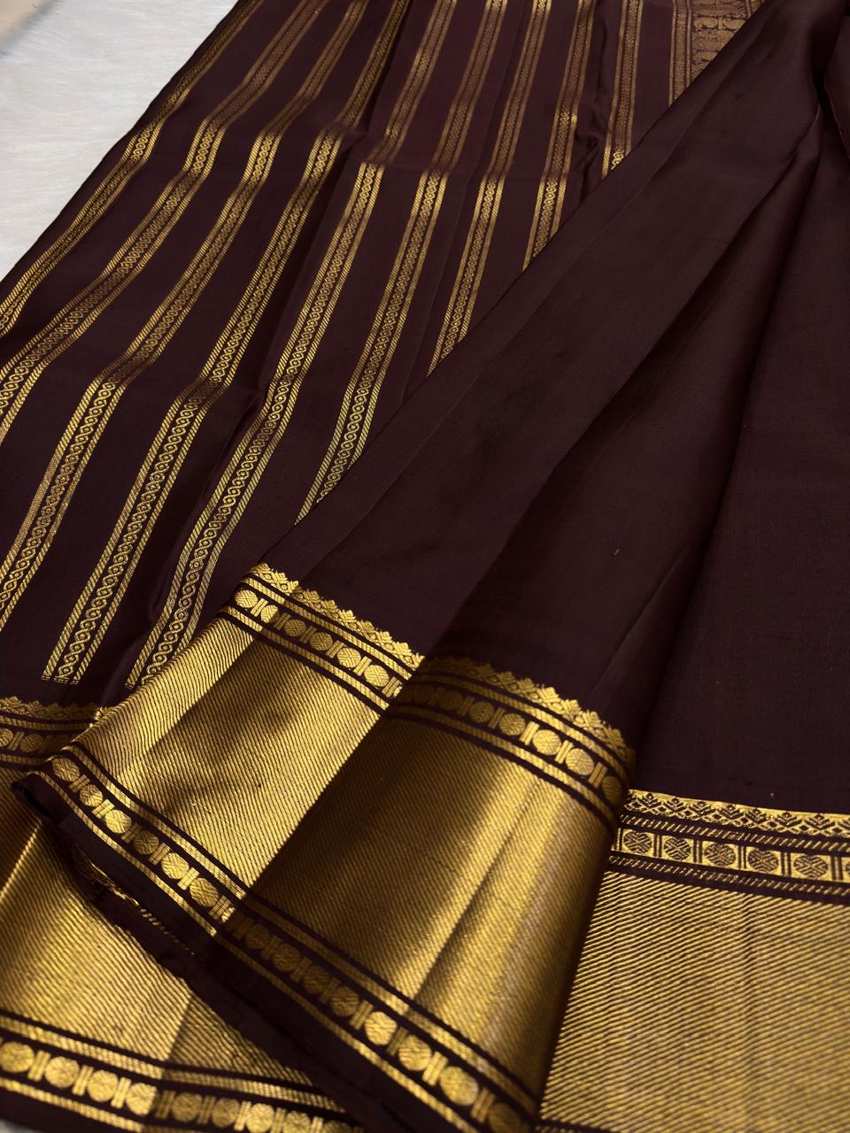 Deep cinnamon brown Vanasringaram Butta Kanchipuram silk saree, folded view showing body and border