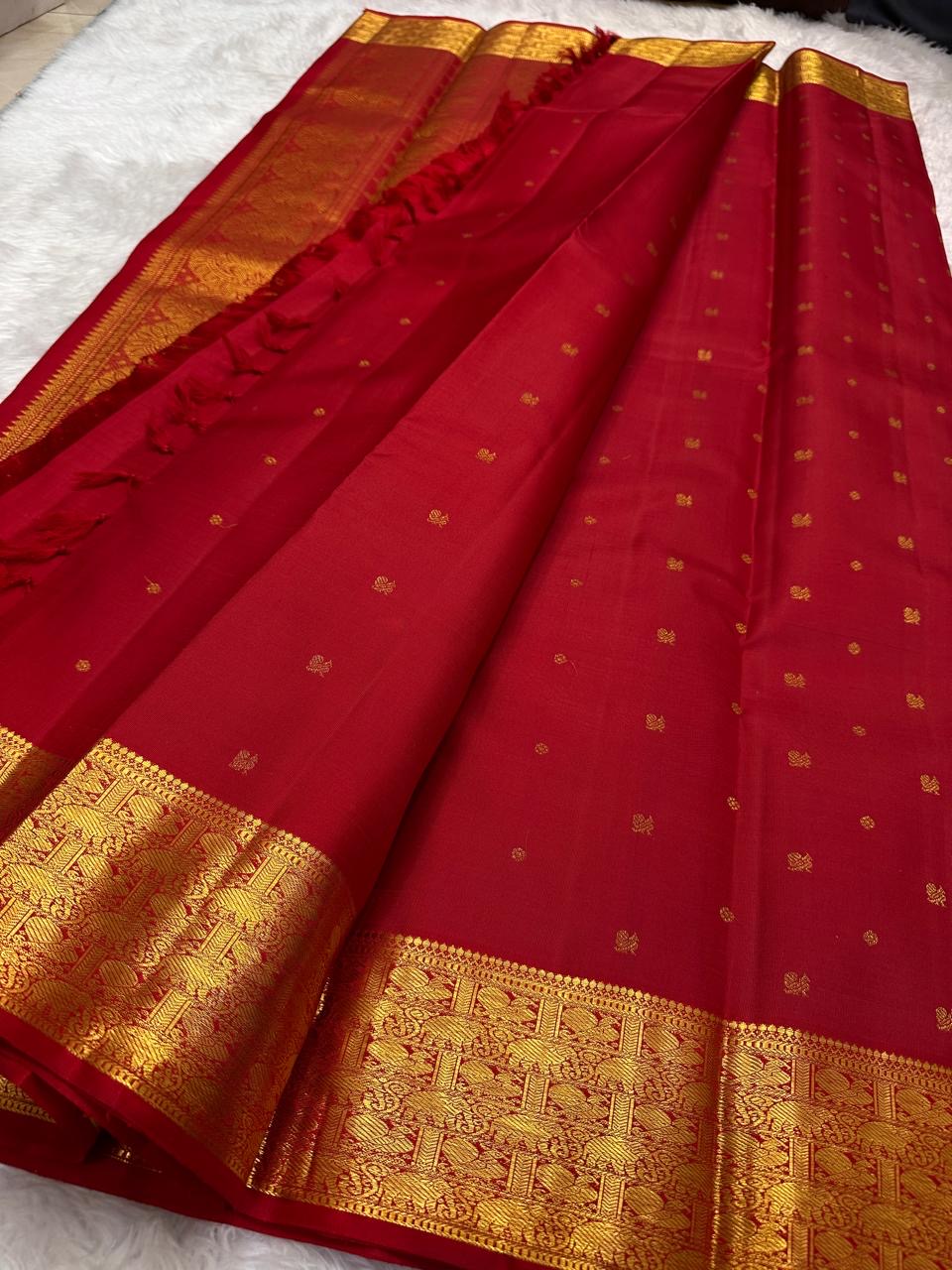 Folded red silk body showing petite gold buttas and richly woven Varisaipet border