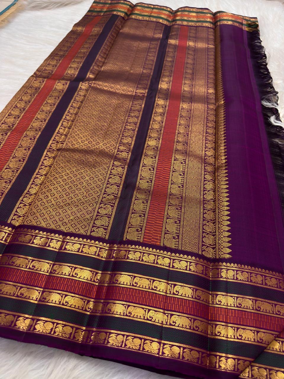Close view of Deep Aubergine Varisaipet border with green, orange and repeated elephant zari stripes.