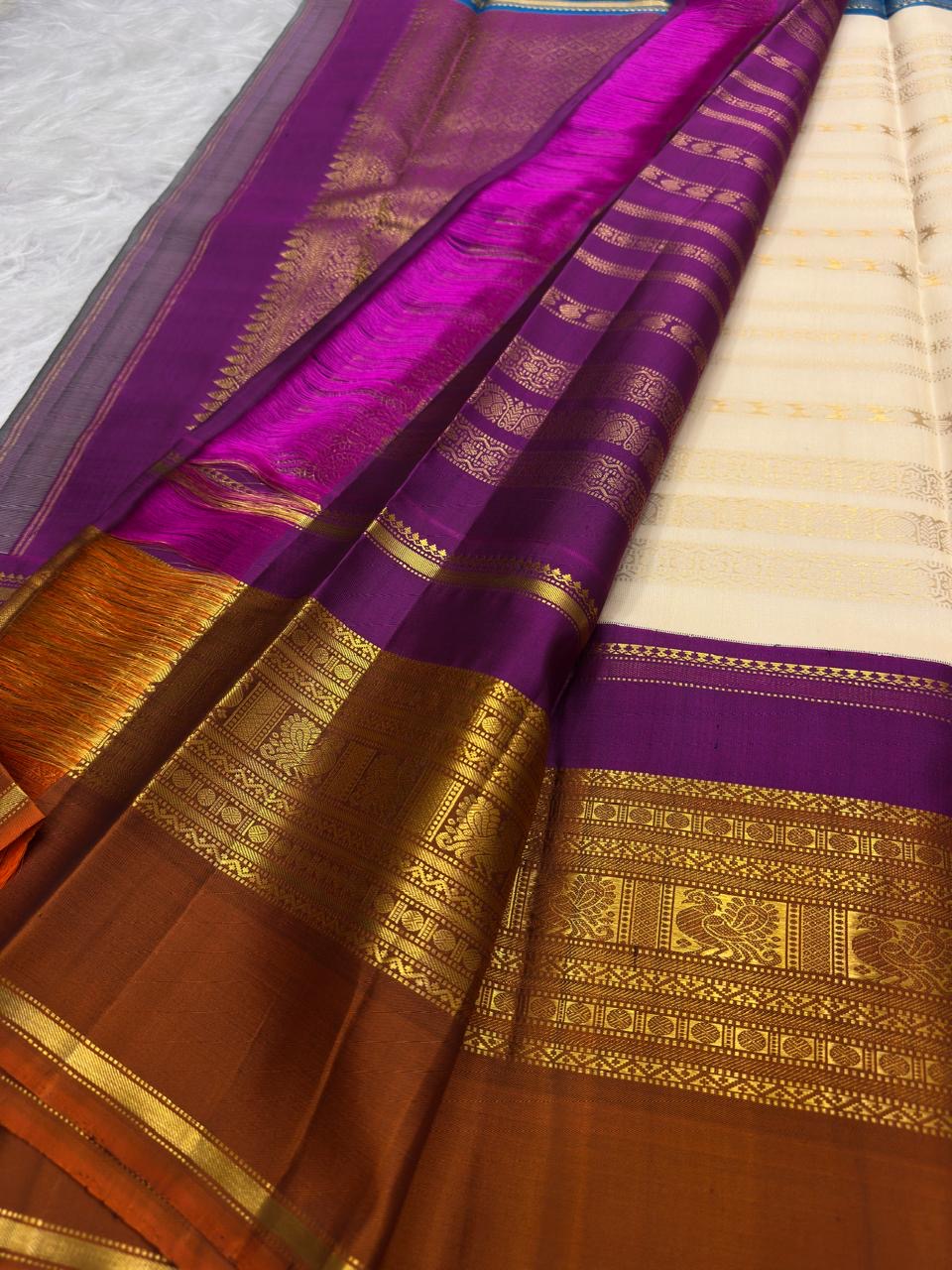 Close view of VarnaJaalam Kanchipuram silk showing ivory zari stripes, purple border and intricate gold bird motifs.