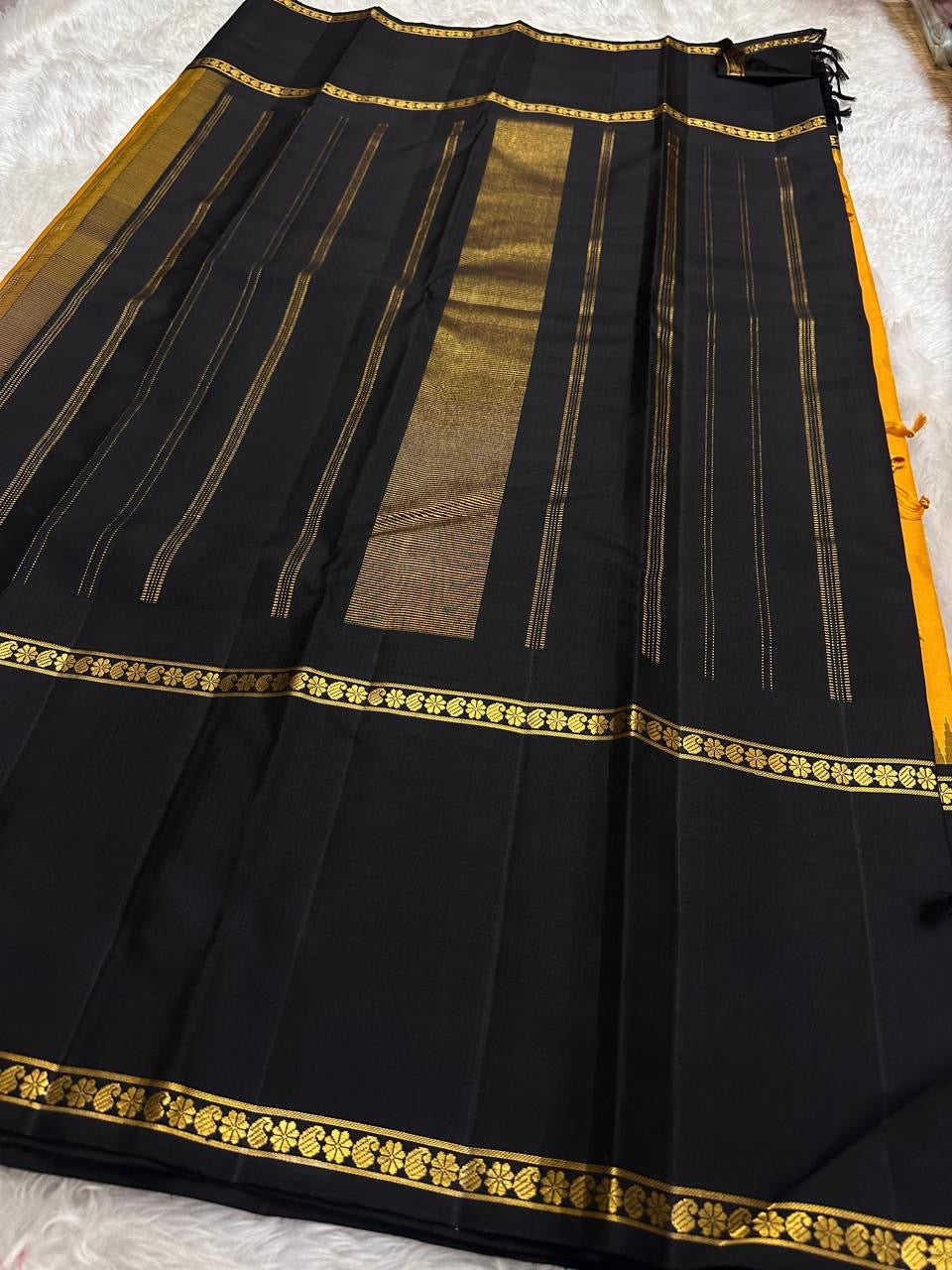 Folded view of amber Kanchi Pattu saree with Rettapet weave and black Veldhari Korvai border — Idam Living
