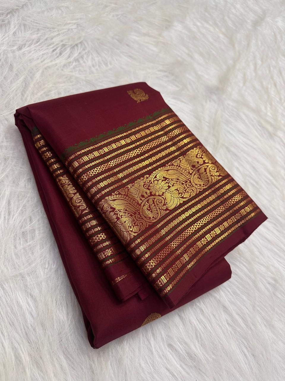Deep Arakku red Kanjivaram Varisaipet saree with Mayil and Kamalam zari buttas.