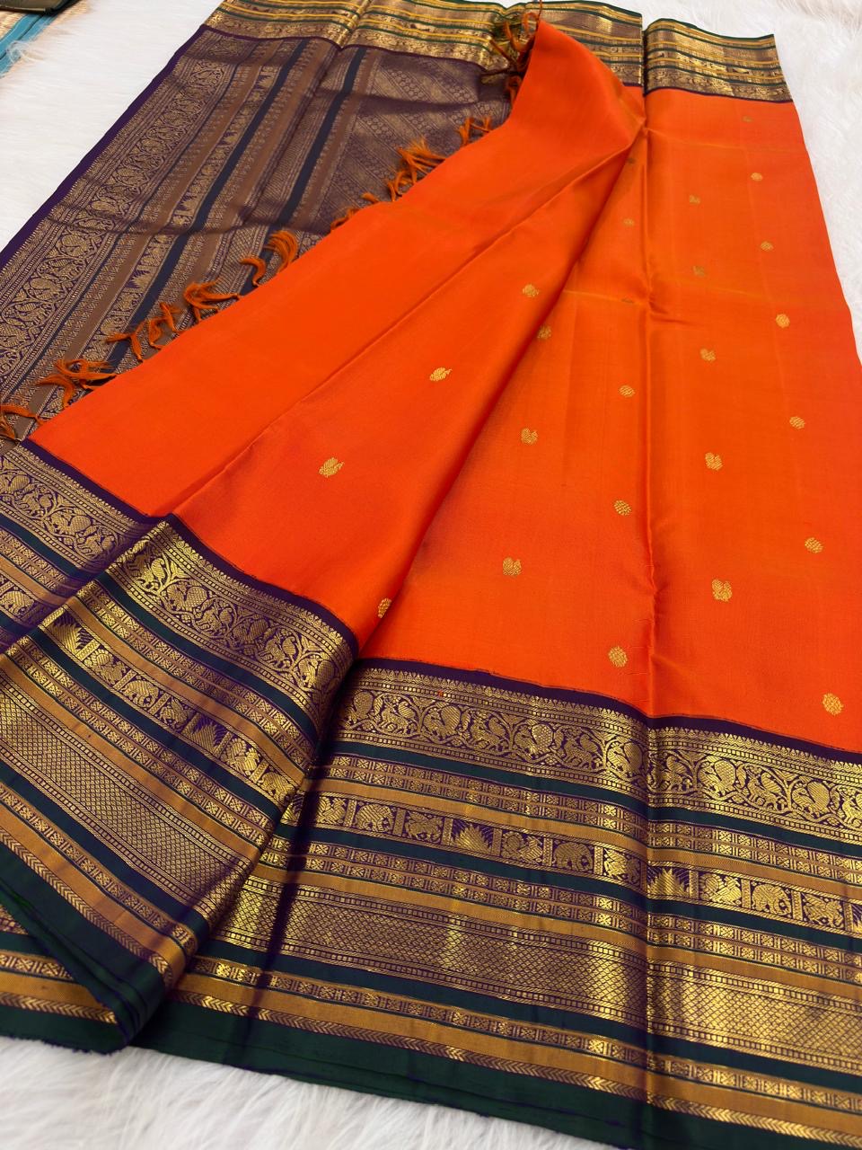 Close-up of heritage Varisaipet border with elephant and peacock zari motifs on Vermilion Orange Kanchi Pattu saree