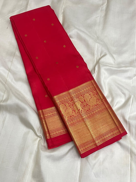 Vermilion Red Kanchipuram Butta saree with broad antique-gold geometric zari border.