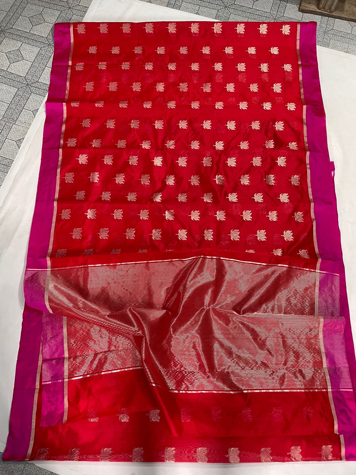 Folded Vermilion Red Chanderi saree showing gold floral motifs and contrasting Rani Pink border.