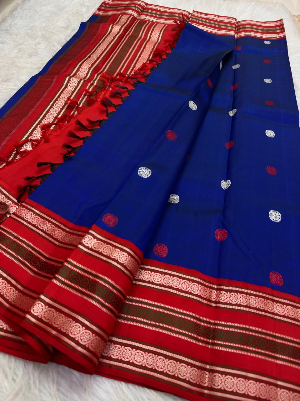Open red pallu showing repeated pale Kamalam flower rows, green thread bands and blue red tasselled edge