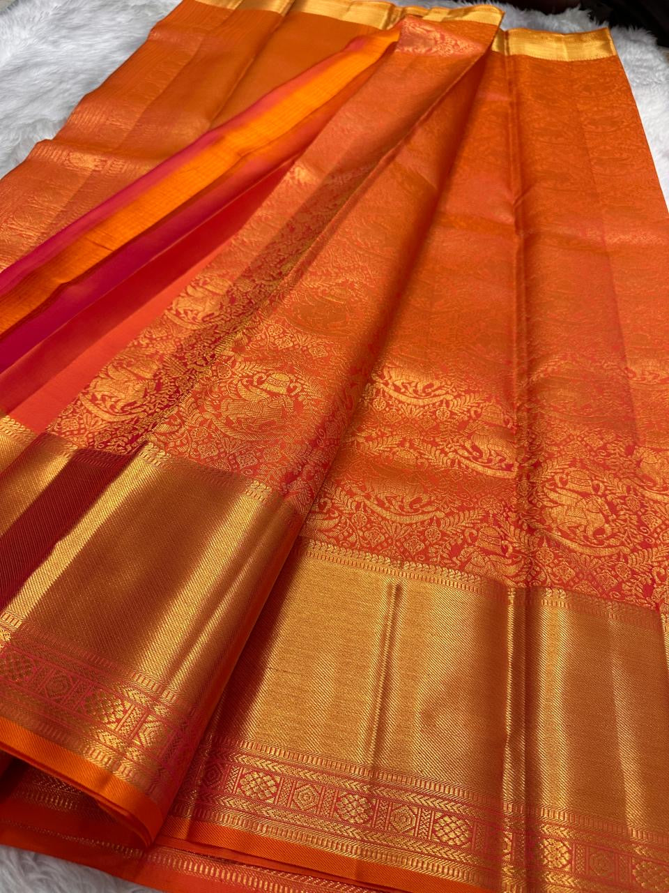 Close view of flying horse and floral zari motifs woven across the warm vermilion silk body.