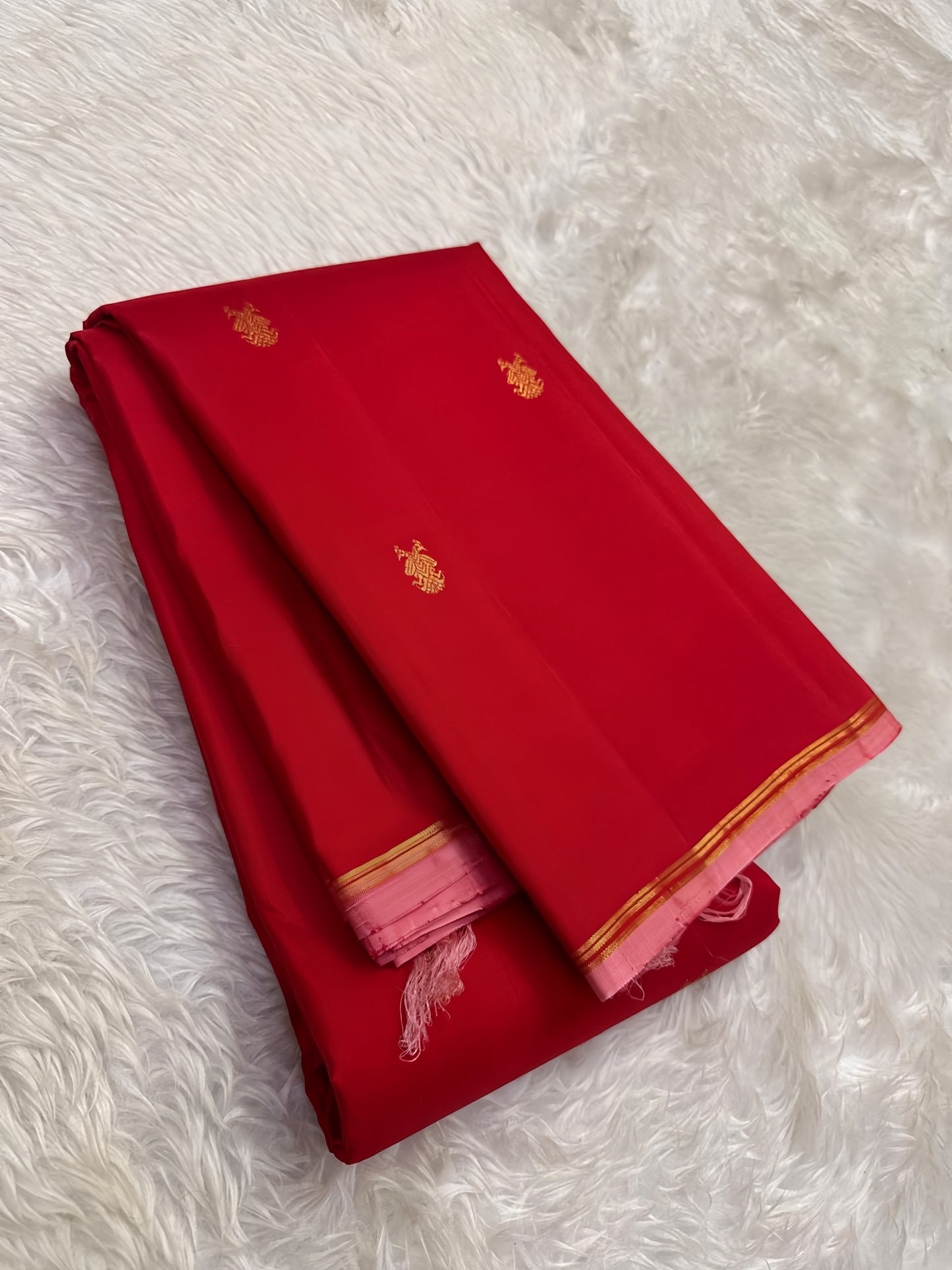 Close view of small Gandaberunda Butta in gold zari on crimson vermilion Kanjivaram silk body with pastel pink selvedge