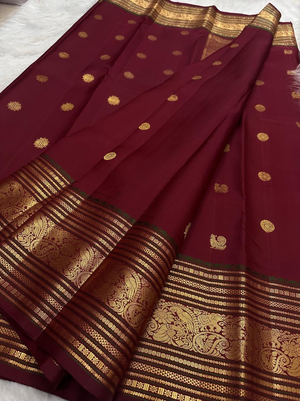 Deep red Kanchipuram silk with gold zari bands and an ornate border.