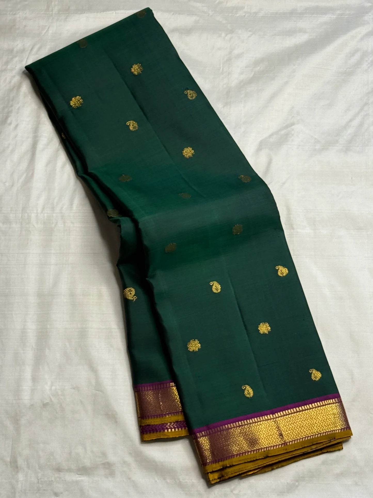 Body close-up of deep emerald green Kanchipuram saree showing paisley and floral buttas