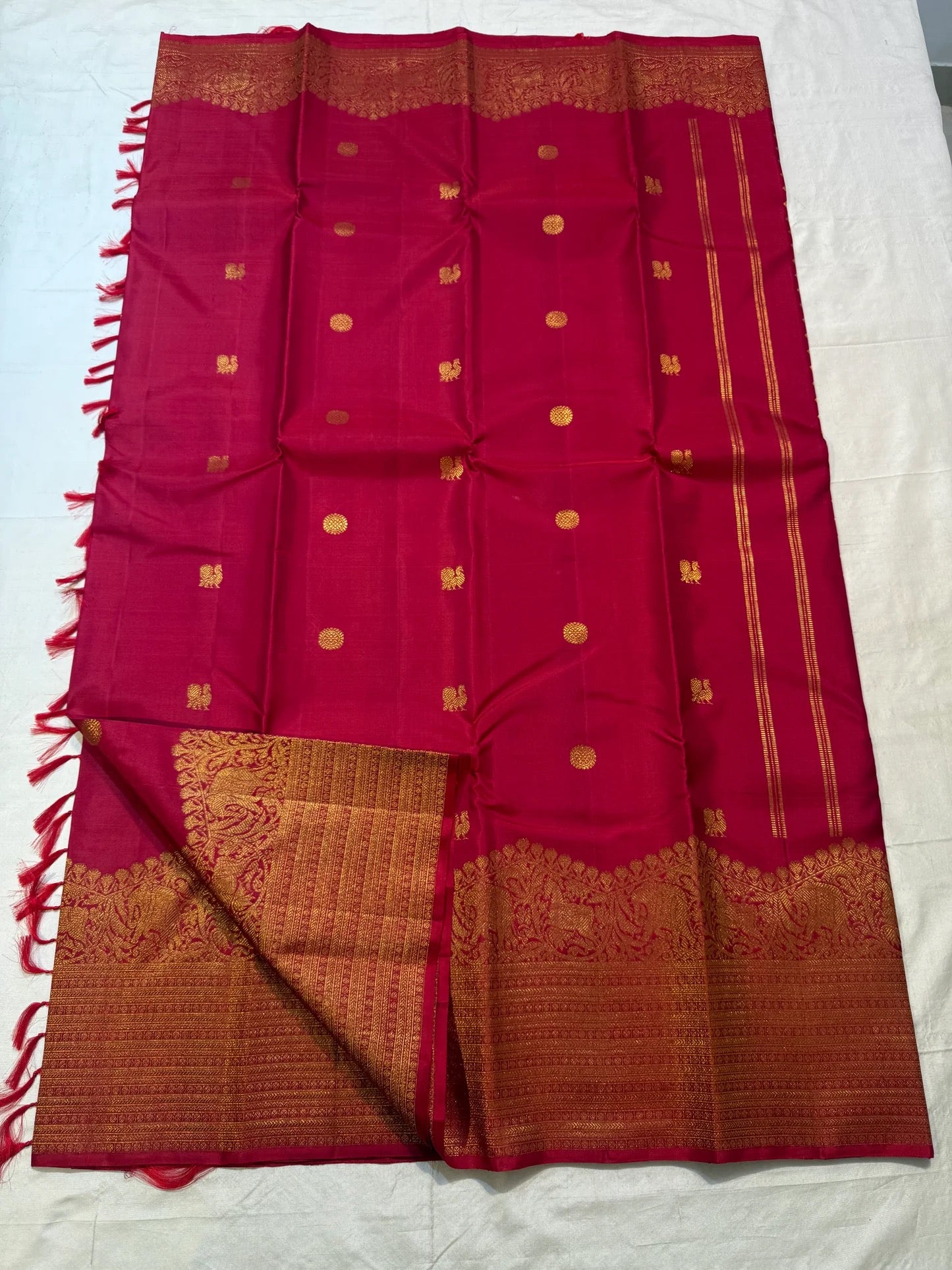 Full Red Deep Pink Kanchipuram Butta saree showing scattered gold zari motifs, broad Turning Border and coordinating blouse piece.