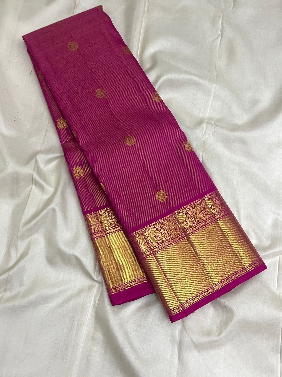 Rounded gold zari medallion butta woven into the Rani Pink Pure Silk body.