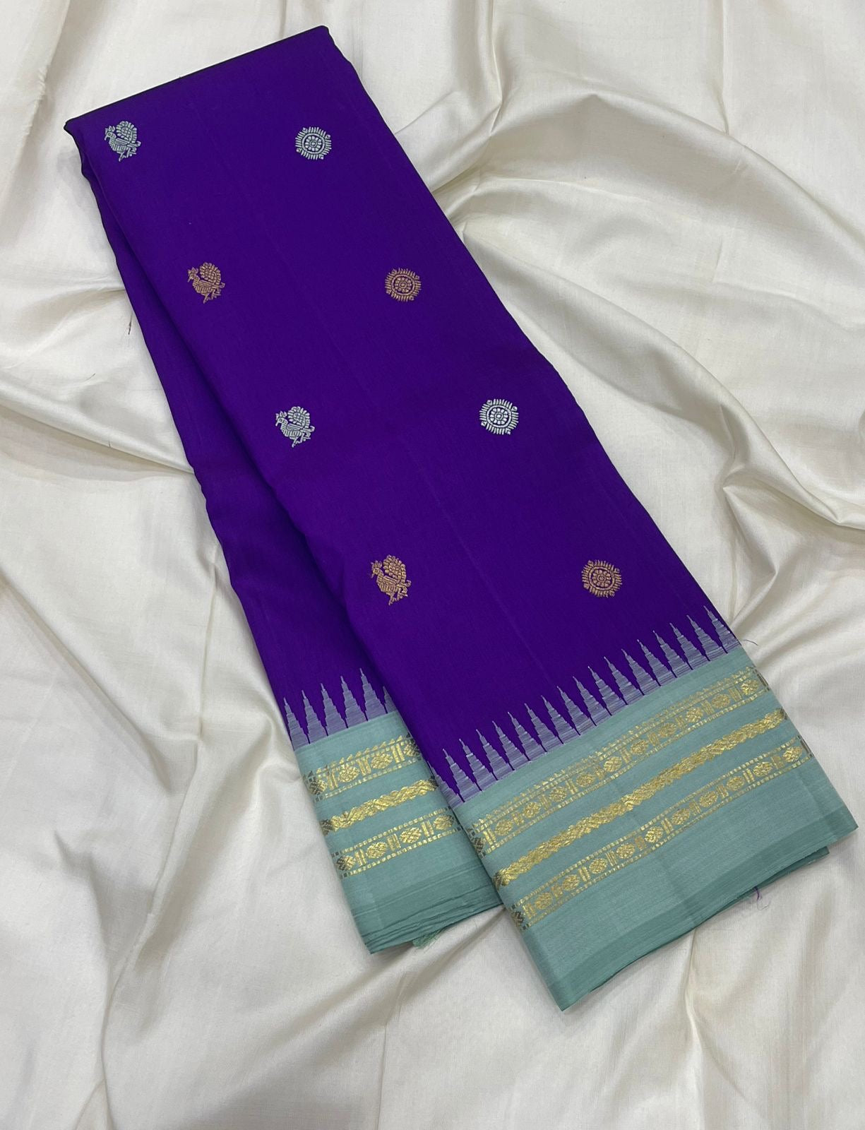 Royal violet blue and ice blue Kanjeevaram silk saree folded showing Mayil Chakram butta body and contrast ice blue Korvai border