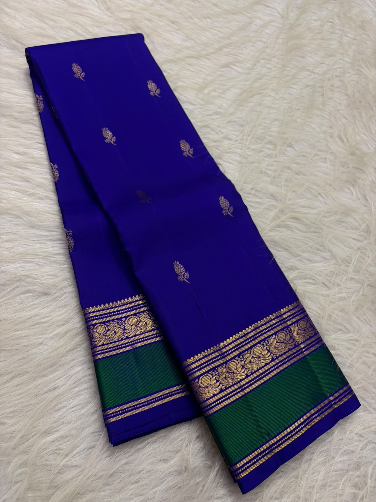 Vivid Neelam Blue and Emerald Green pure silk Kanchipuram Varisaipet saree, full saree folded for display.