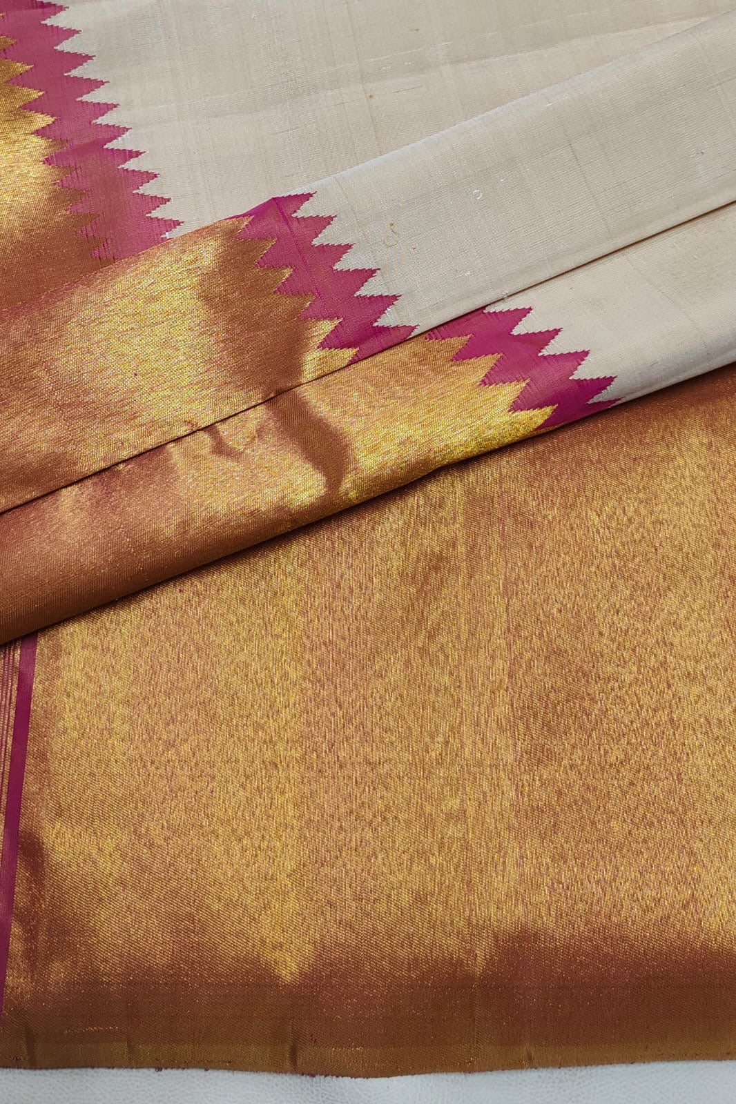 Warm Ivory pure silk Kanjivaram Ettukol saree with Rani Pink temple edge and antique-gold zari border.