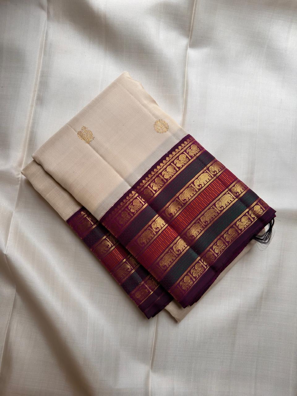 Warm Ivory Pure Silk Kanchipuram saree with petite gold buttas and handwoven multi-stripe elephant zari border.