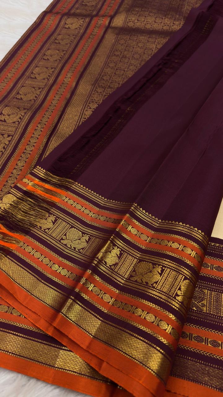 Rich Aubergine Purple pallu with dense antique-gold zari weaving and Burnt Orange registers.