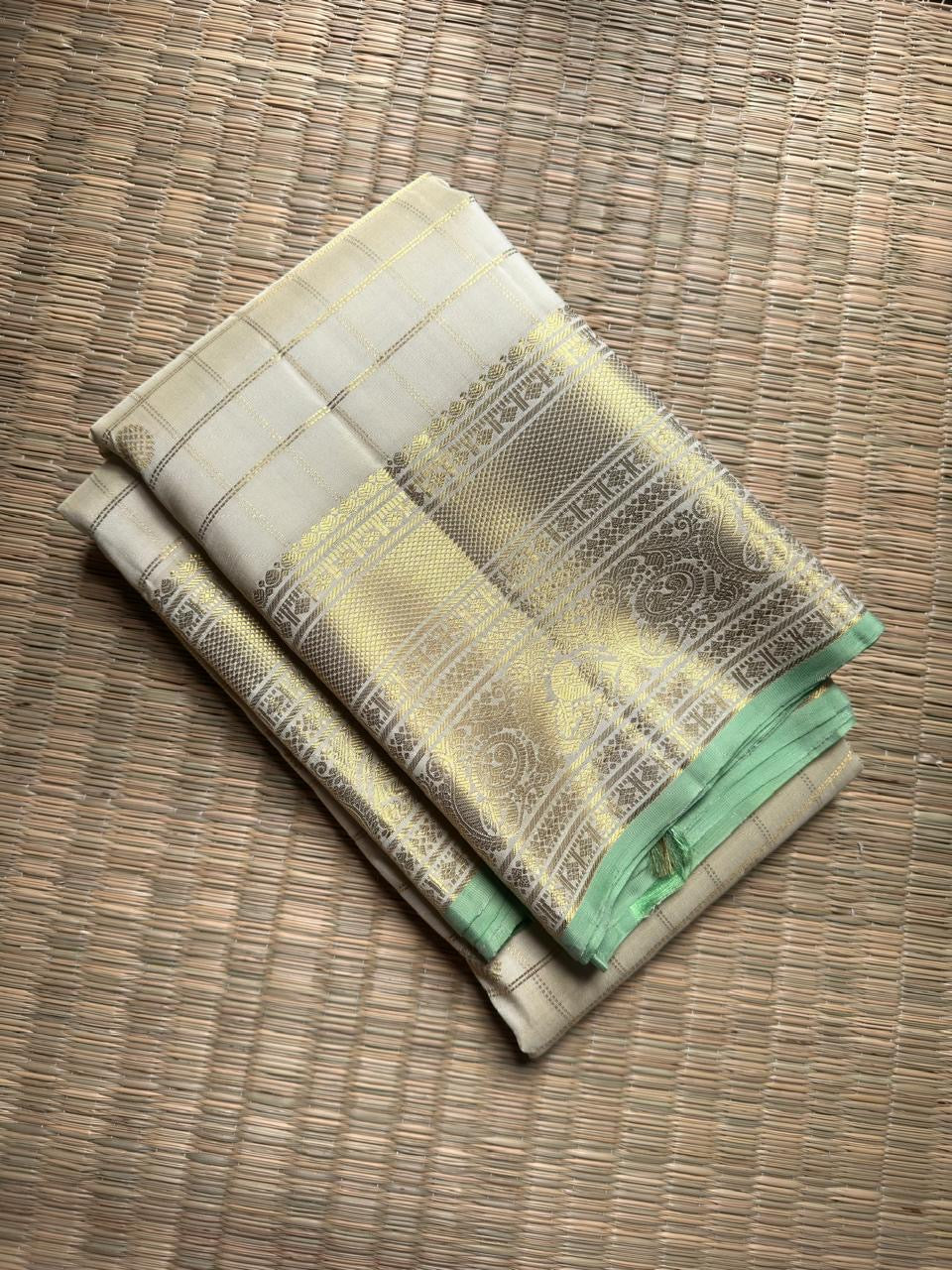 Warm Ivory Zari Kattam silk showing fine checked lines, petite Kamalam buttas and broad metallic zari border.