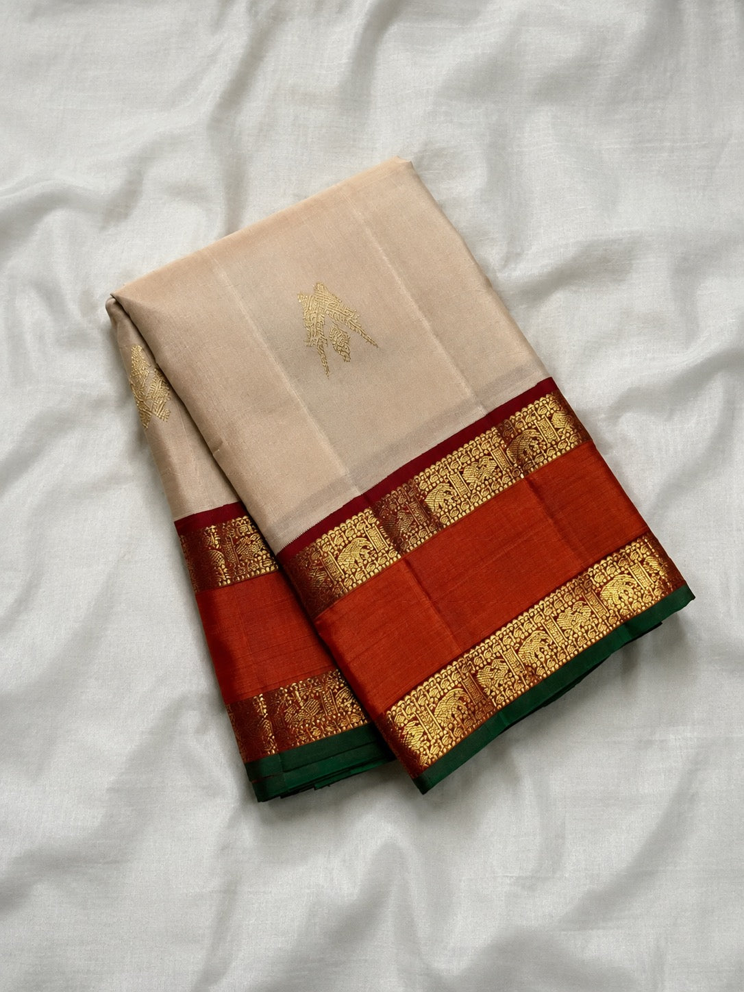 Kanchipuram Korvai saree showing burnt orange border, intricate gold zari bands and forest-green silk edge.