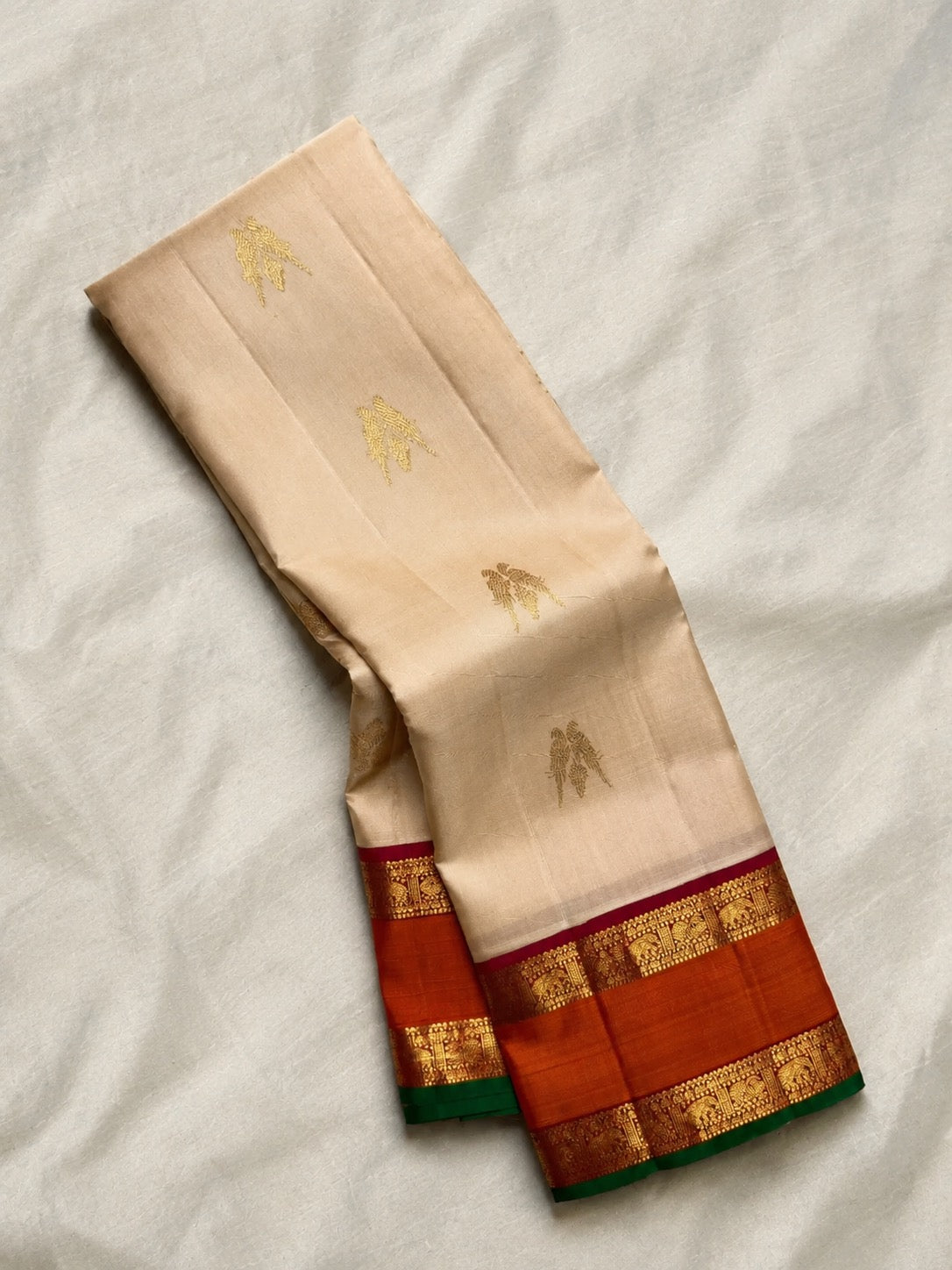 Warm ivory Pure Silk Kanchipuram Korvai saree with twin bird zari buttas and burnt orange border.