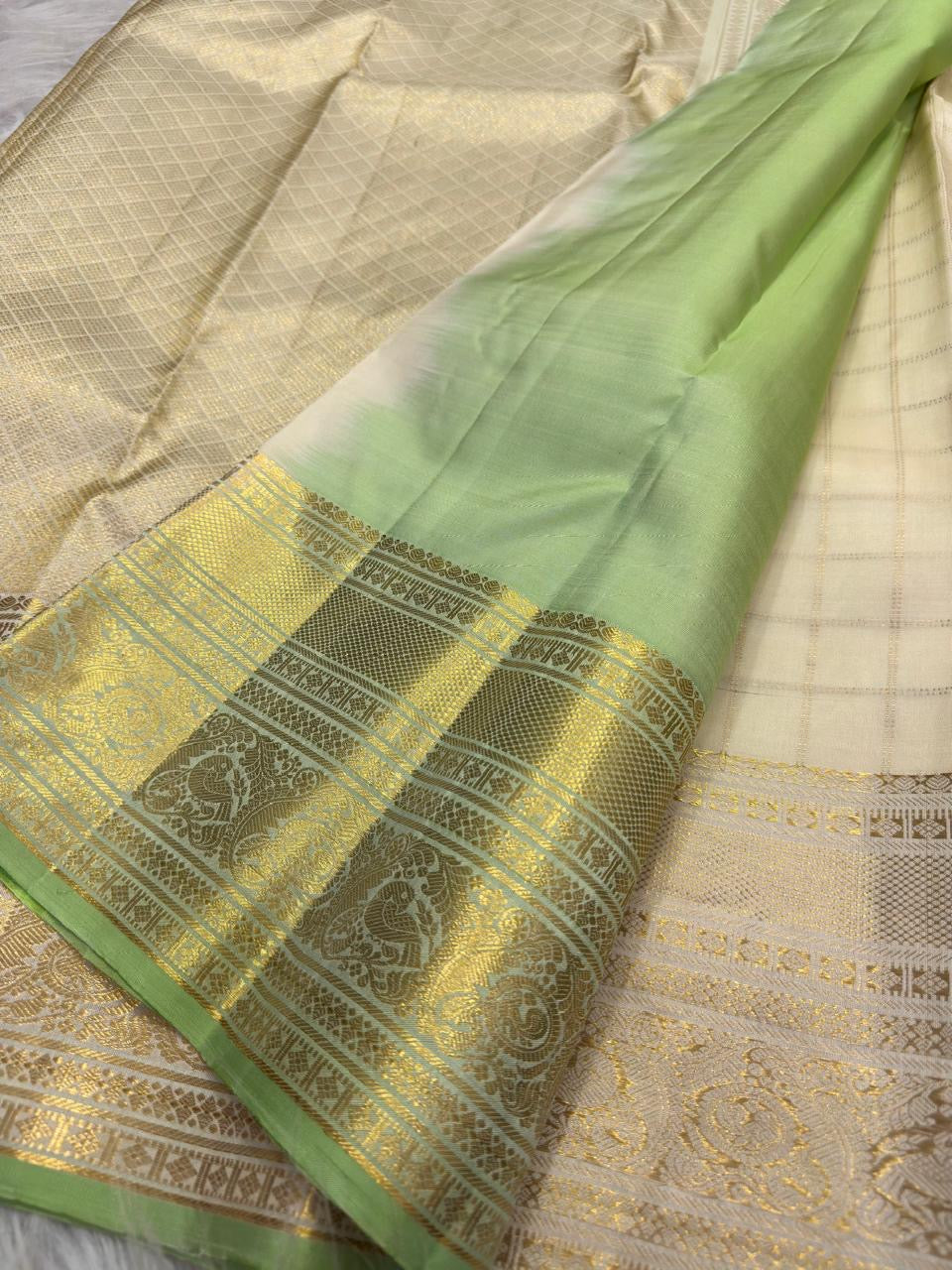 Folded Warm Ivory and lavender Kanchipuram Zari Kattam sarees showing ornate metallic borders and Mint Green edging.