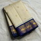 Warm Ivory Kanchipuram silk body with spaced gold zari buttas and peacock-neck colour Korvai border.