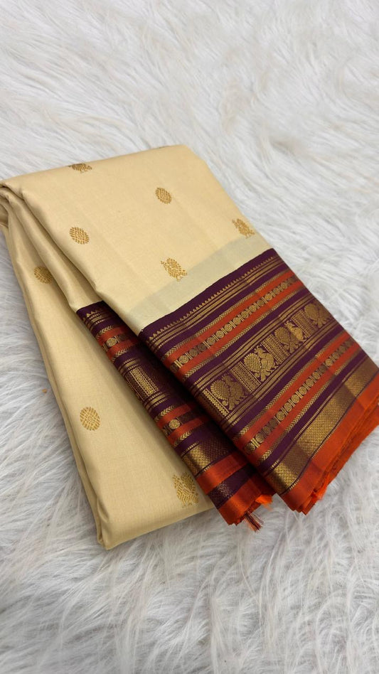 Warm Ivory Kanchipuram silk saree with spaced antique-gold zari motifs and richly layered Varisaipet border.