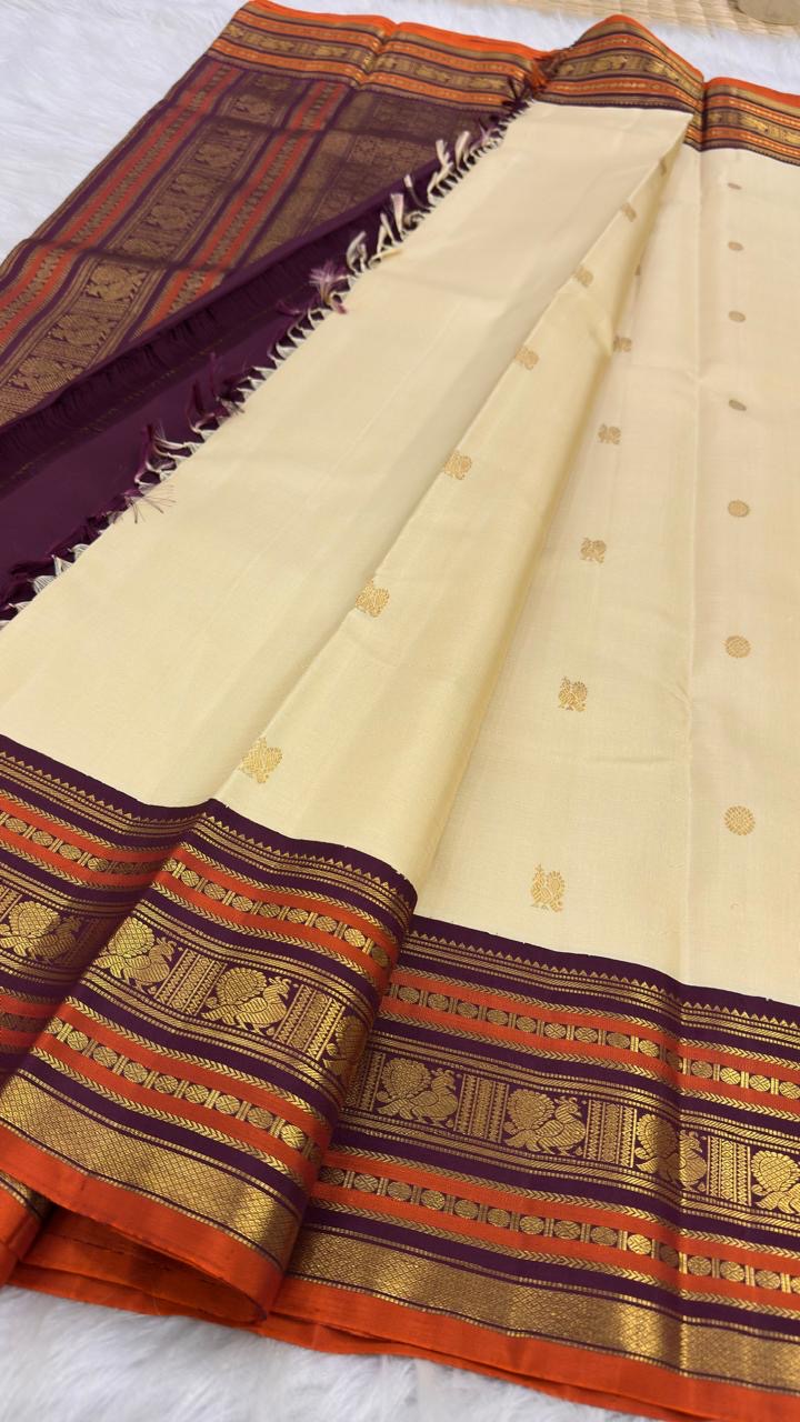 Warm Ivory pure silk Kanjivaram Varisaipet saree with Deep Aubergine Purple Burnt Orange and antique-gold zari border.