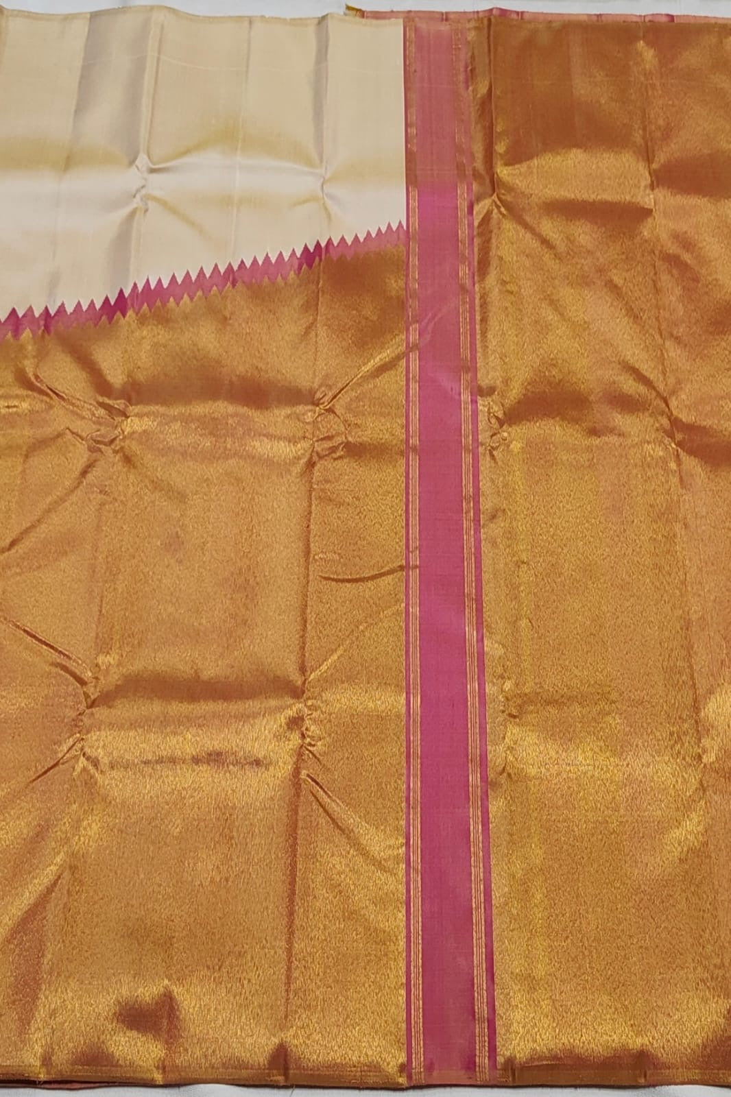 Ivory Kanchipuram silk Ettukol saree with broad antique-gold border and pink triangular edging.