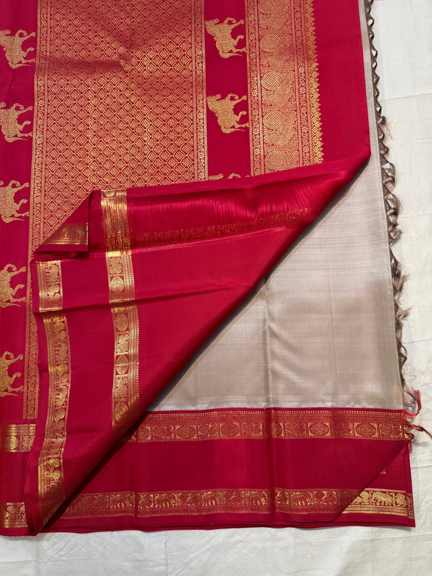 Folded view of warm ivory Korvai saree with rani pink zari border