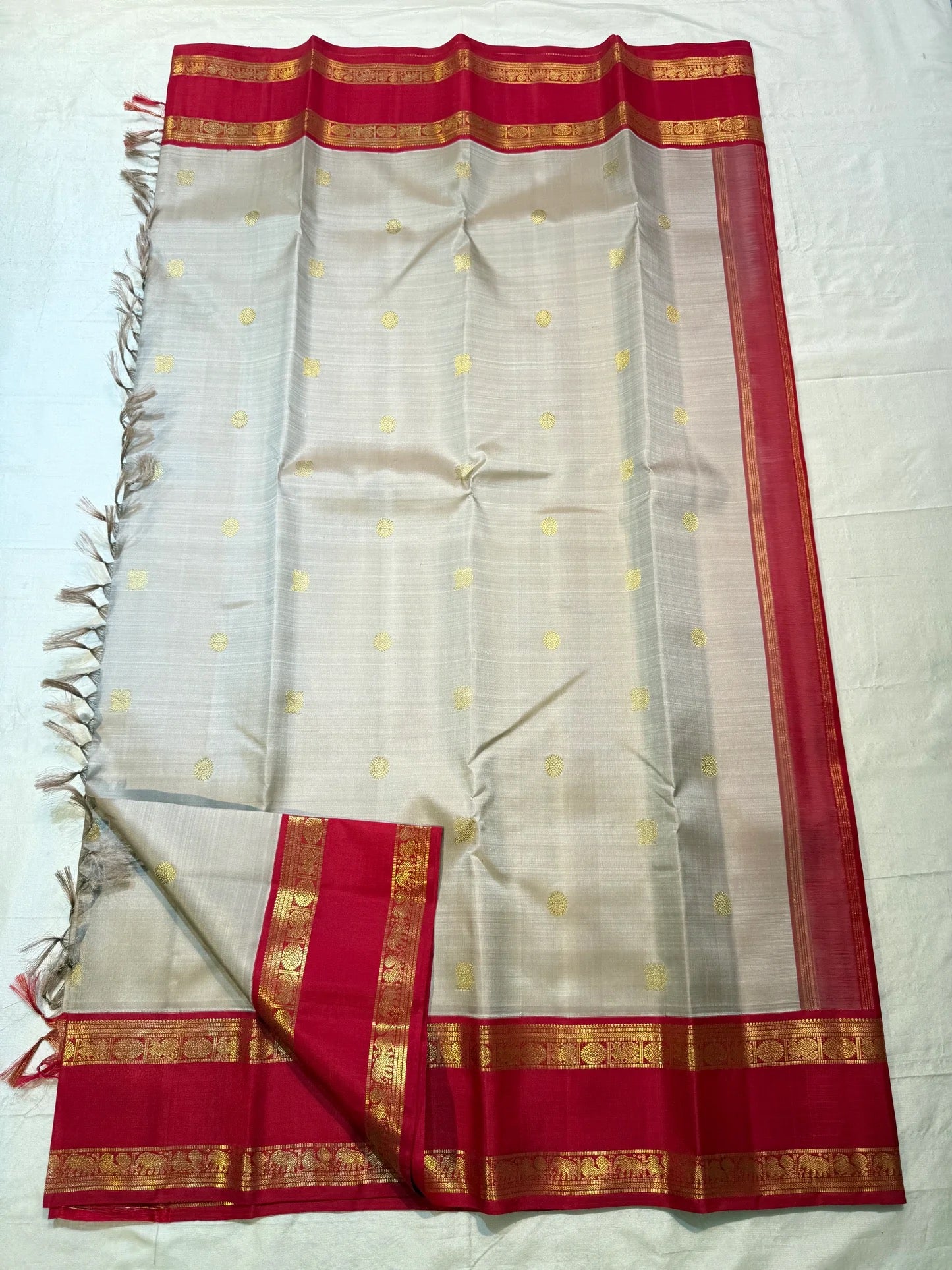 Full laid-flat view of warm ivory saree with gold zari buttas and pink border
