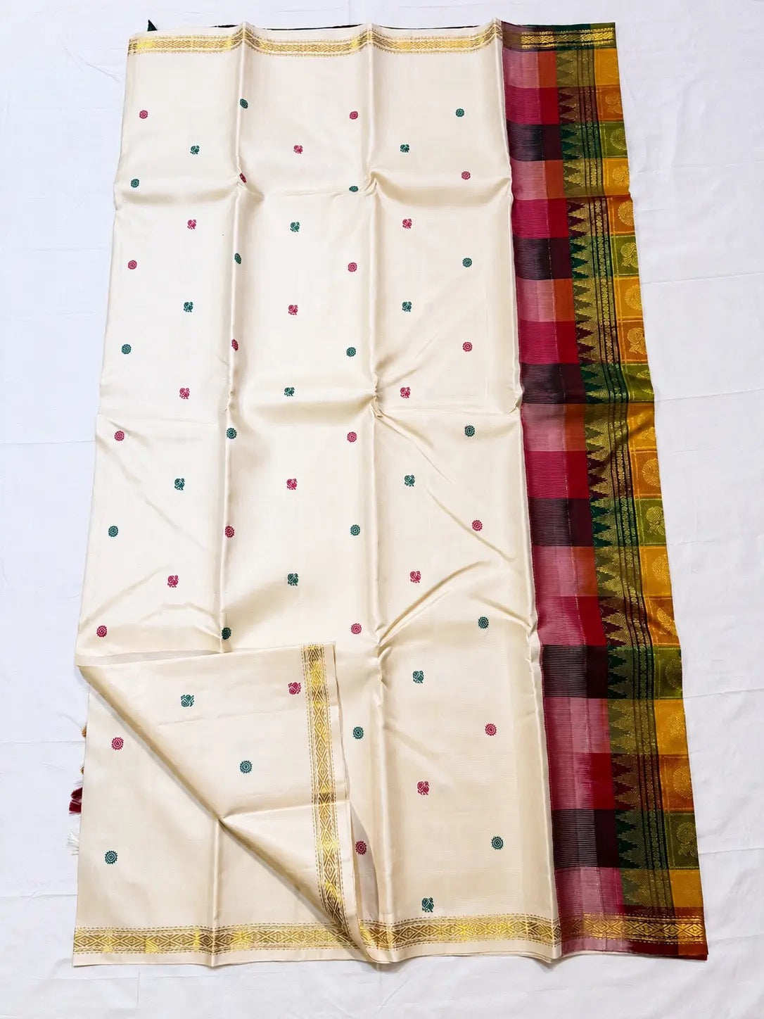 Warm Ivory Kanjeevaram silk body with deep green and raspberry-maroon thread buttas.