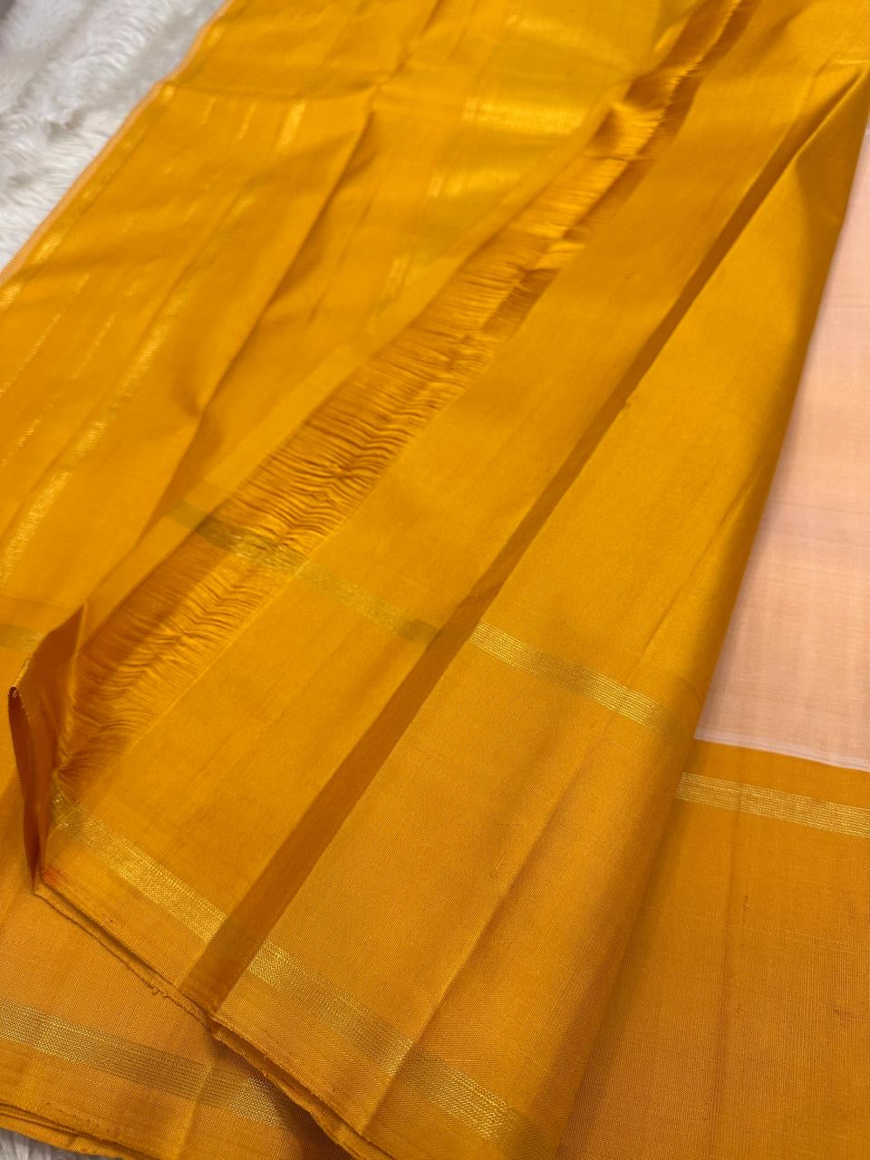 White Kancheepuram silk saree with a coordinated mustard pallu