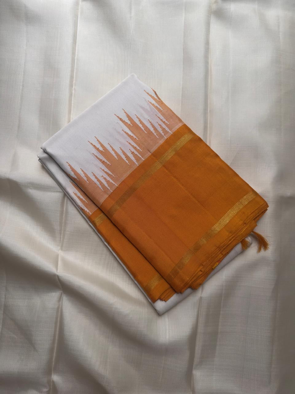 Mustard-toned thazampoo reku border on a white Kanchipuram saree