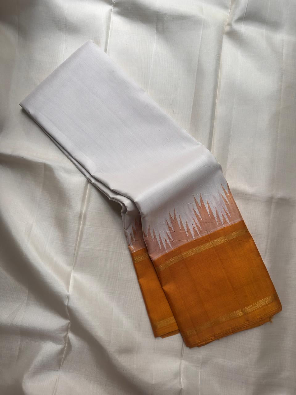 White handwoven Pure Silk Kanchipuram korvai saree folded to show the mustard border