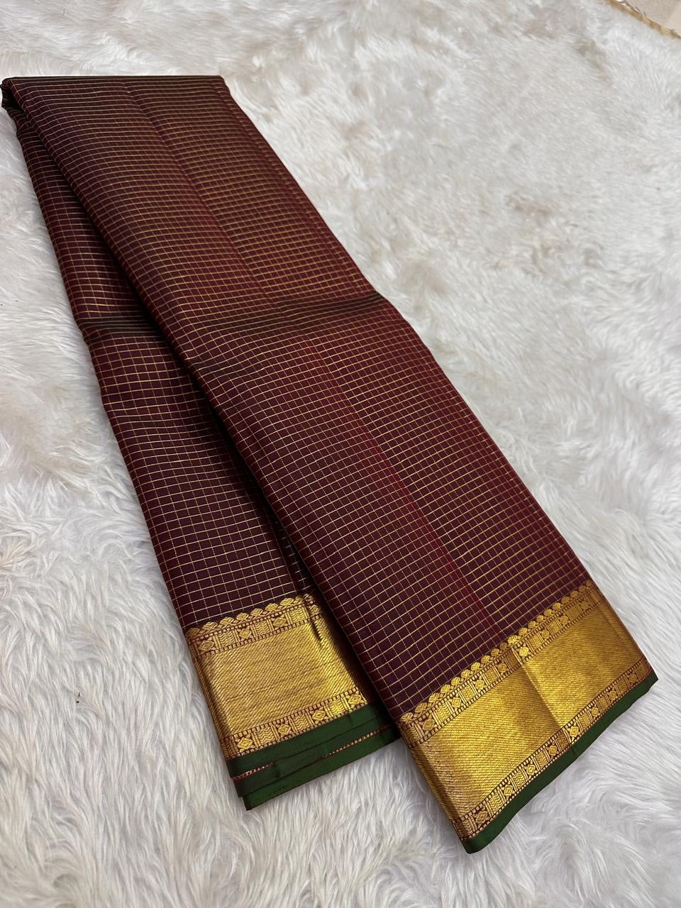 Diagonal zari woven pallu in antique gold cascading across burgundy deep coffee brown silk ground