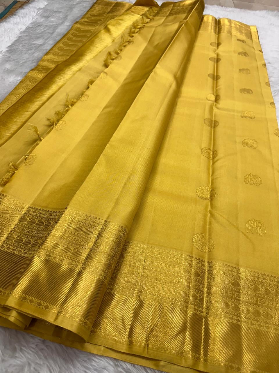 Close view of broad gold zari Kanchipuram border with detailed handwoven peacock motifs.