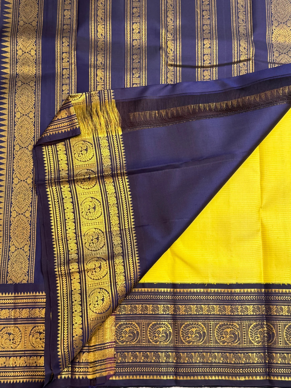 Yellow silk set against navy and gold border with peacock motifs and repeated decorative bands