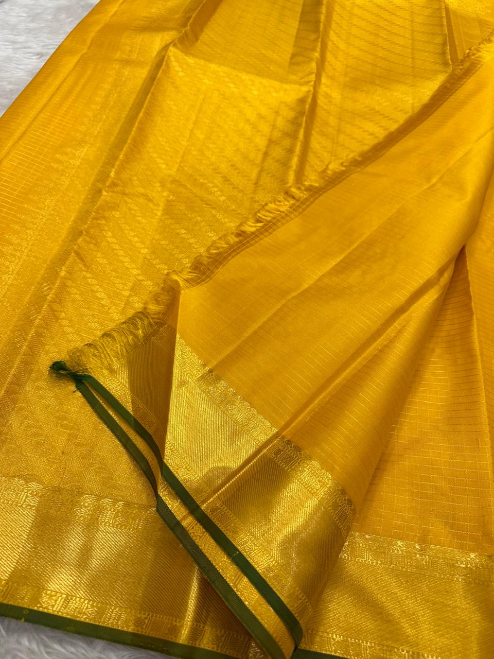 Thick antique gold zari woven border with floral and geometric motifs on yellow Kanjivaram saree